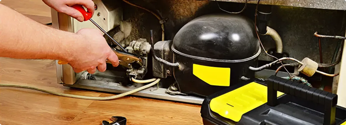 Refrigerator repair technician fixing the compressor and wiring in Willow Beach, AZ