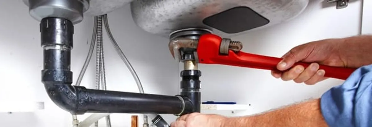 Garbage disposal repair technician tightening the sink drain and disposal connection in Henderson, NV