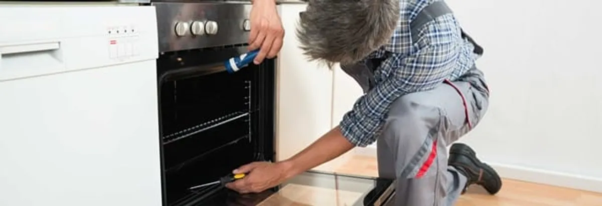 Oven repair technician inspecting and servicing an electric oven in Henderson, NV