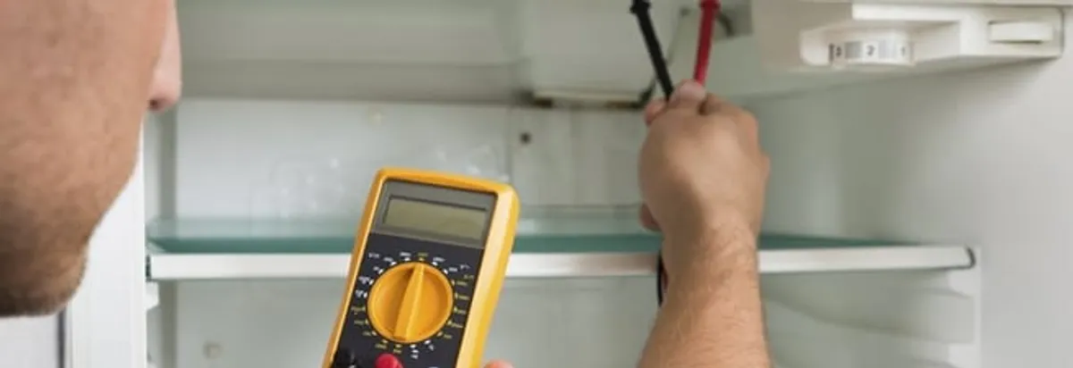 Refrigerator repair technician testing electrical components with a multimeter in Henderson, NV
